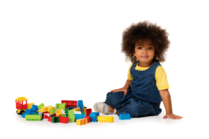 A child sits on the floor next to some Lego-style blocks.